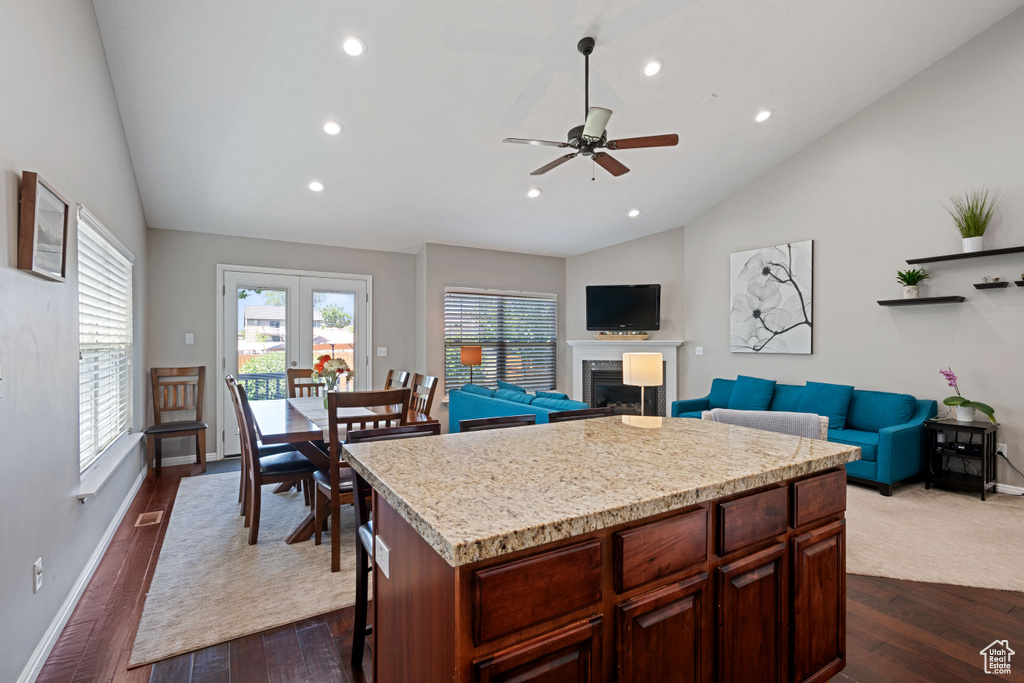 Kitchen featuring vaulted ceiling, a ceiling fan, recessed lighting, dark wood finished floors, and a fireplace
