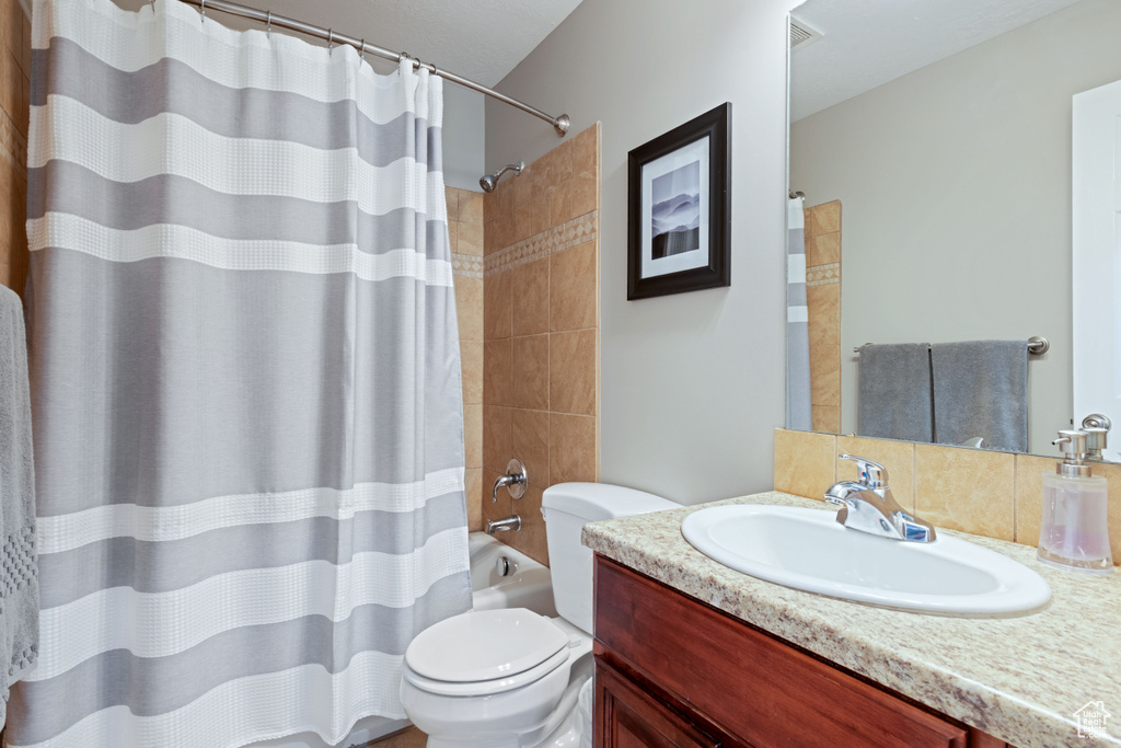 Full bathroom with vanity, toilet, and shower / bath combination with curtain