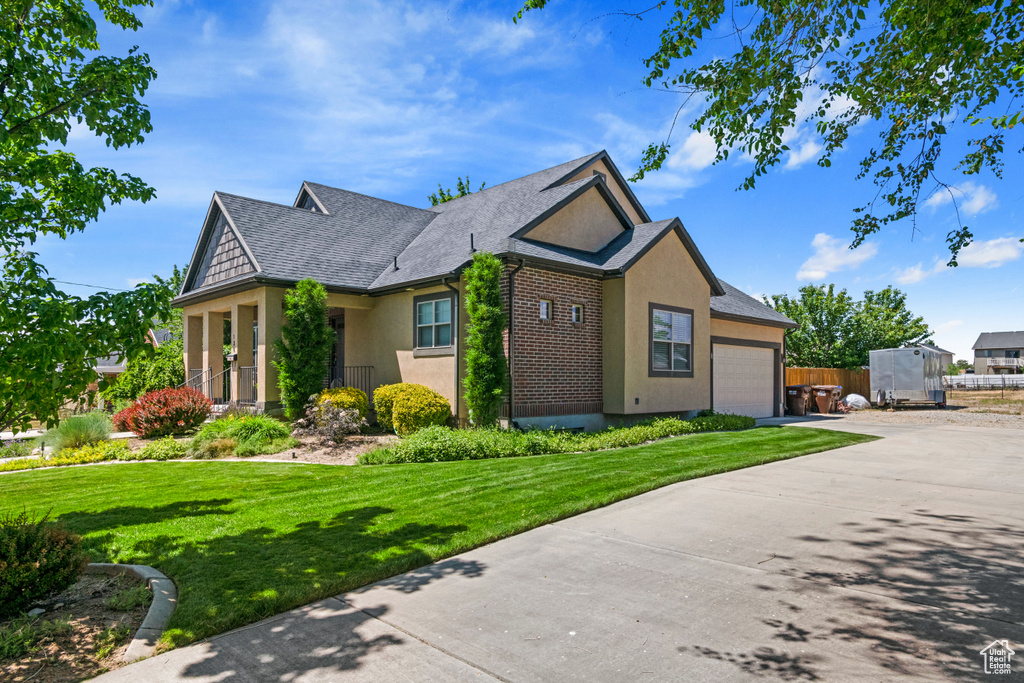 View of front of home with an attached garage, concrete driveway, stucco siding, and roof with shingles