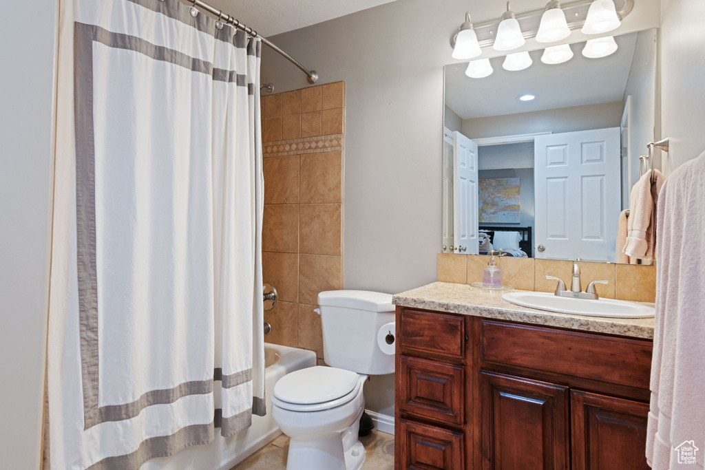 Full bathroom featuring vanity, shower / bath combo, and toilet