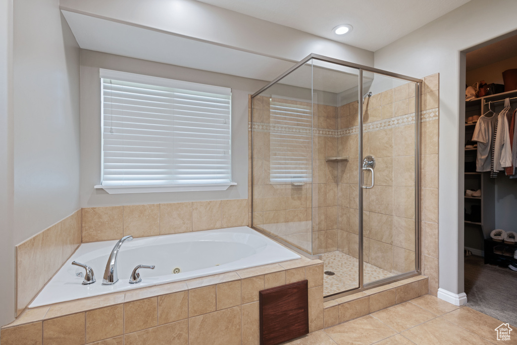 Full bath featuring a whirlpool tub, a shower stall, a spacious closet, tile patterned flooring, and healthy amount of natural light