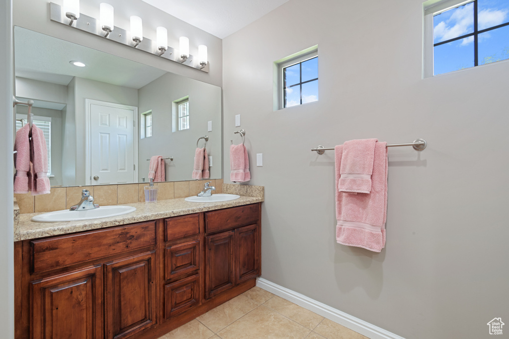 Full bathroom featuring double vanity, tile patterned floors, and baseboards