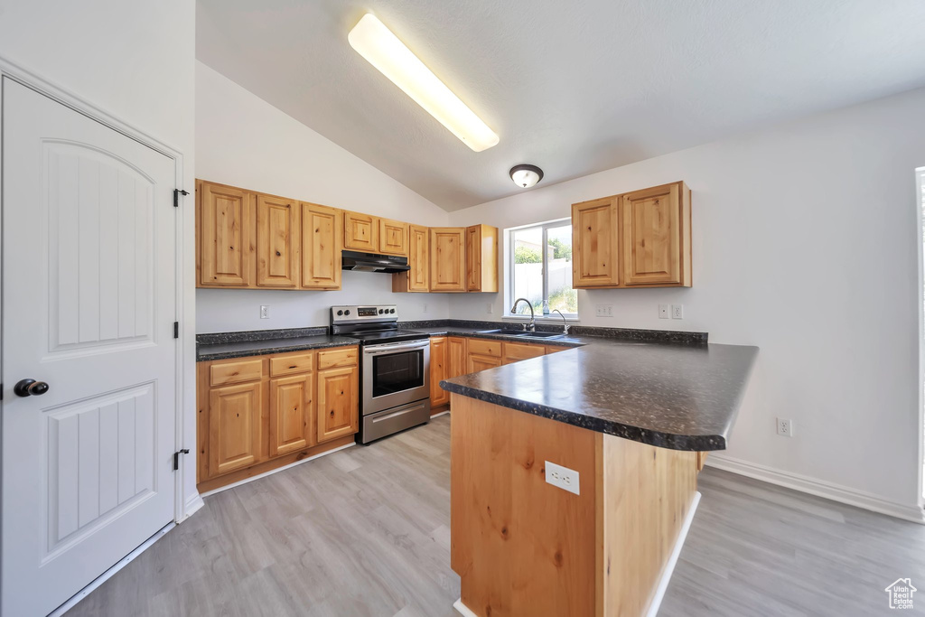 Kitchen featuring stainless steel range with electric stovetop, a sink, vaulted ceiling, a peninsula, and dark countertops