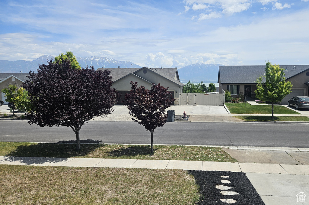 View of asphalt street featuring a gate, sidewalks, a mountain view, and curbs