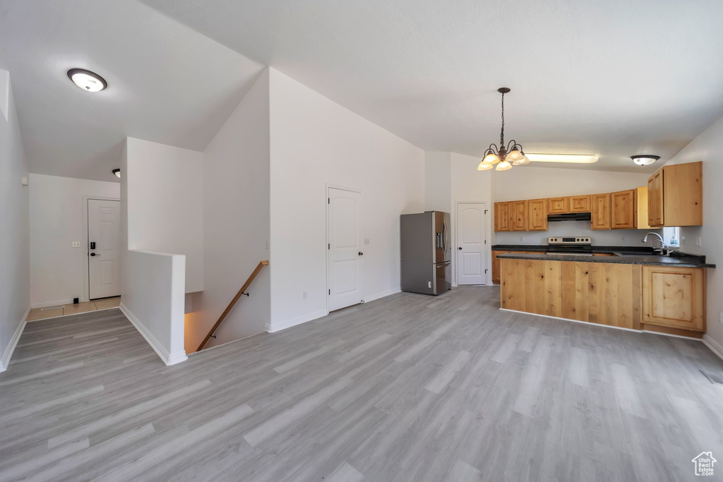 Kitchen with lofted ceiling, appliances with stainless steel finishes, dark countertops, light wood finished floors, and baseboards