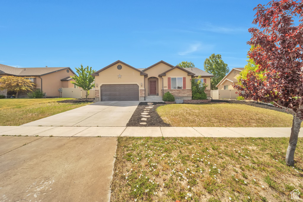 Ranch-style house featuring stucco siding, a garage, driveway, and stone siding