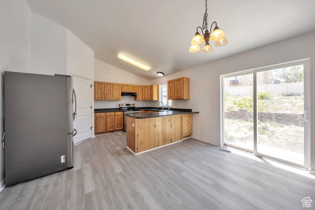 Kitchen featuring stainless steel appliances, a sink, a peninsula, dark countertops, and a chandelier
