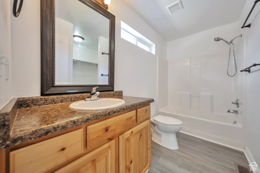 Full bath with toilet, vanity, washtub / shower combination, and wood finished floors
