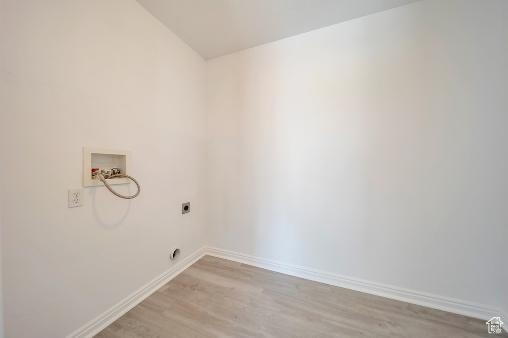 Laundry room with hookup for a washing machine, electric dryer hookup, light wood-type flooring, and baseboards