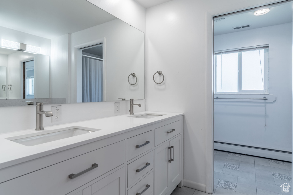 Bathroom featuring baseboard heating, double vanity, and tile patterned floors