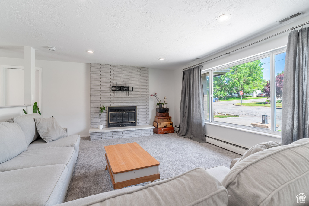 Carpeted living area featuring a baseboard radiator, a brick fireplace, and recessed lighting