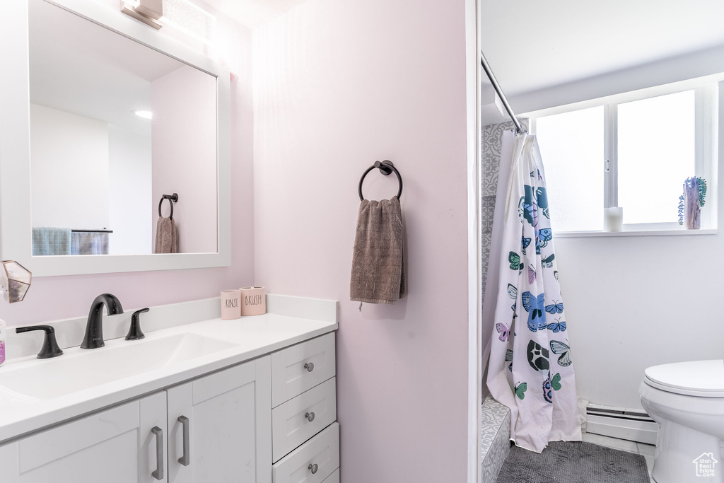 Full bathroom featuring baseboard heating, vanity, toilet, a shower with curtain, and tile patterned flooring