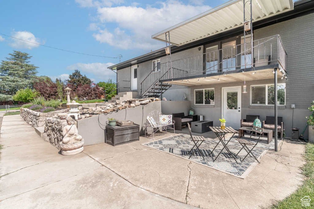 View of patio featuring an outdoor living space, stairs, and a balcony