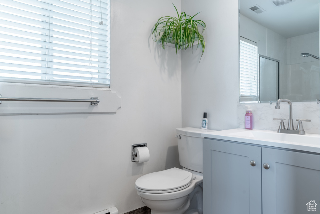 Bathroom featuring vanity, toilet, and a shower