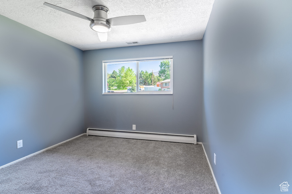 Unfurnished room with a baseboard heating unit, carpet floors, a textured ceiling, a ceiling fan, and baseboards