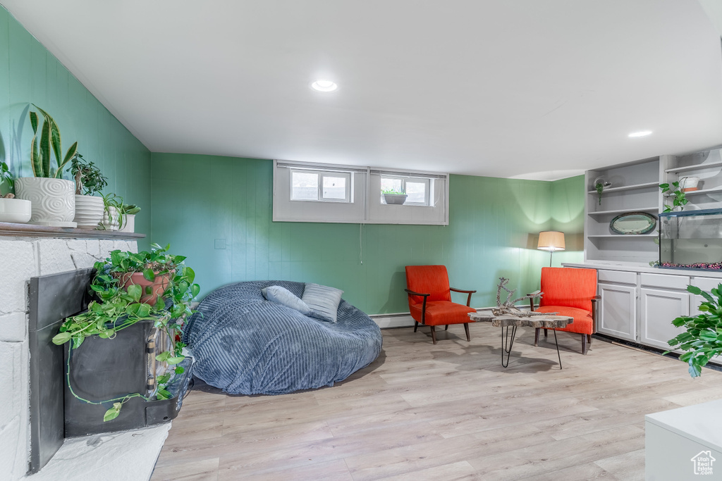 Living area with light wood-type flooring, a baseboard radiator, a fireplace, and recessed lighting
