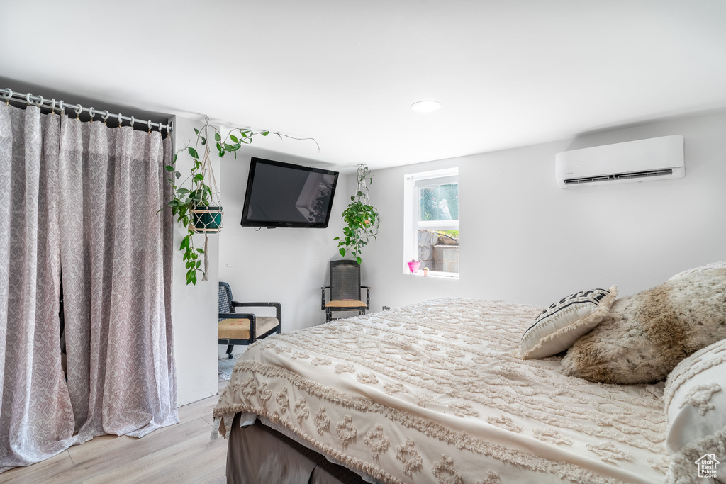 Bedroom featuring a wall mounted air conditioner, light wood-type flooring, and recessed lighting