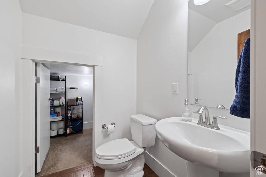 Bathroom featuring lofted ceiling, a sink, toilet, and wood finished floors
