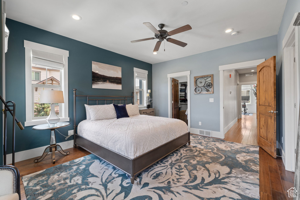 Bedroom with baseboards, wood finished floors, a spacious closet, recessed lighting, and ceiling fan