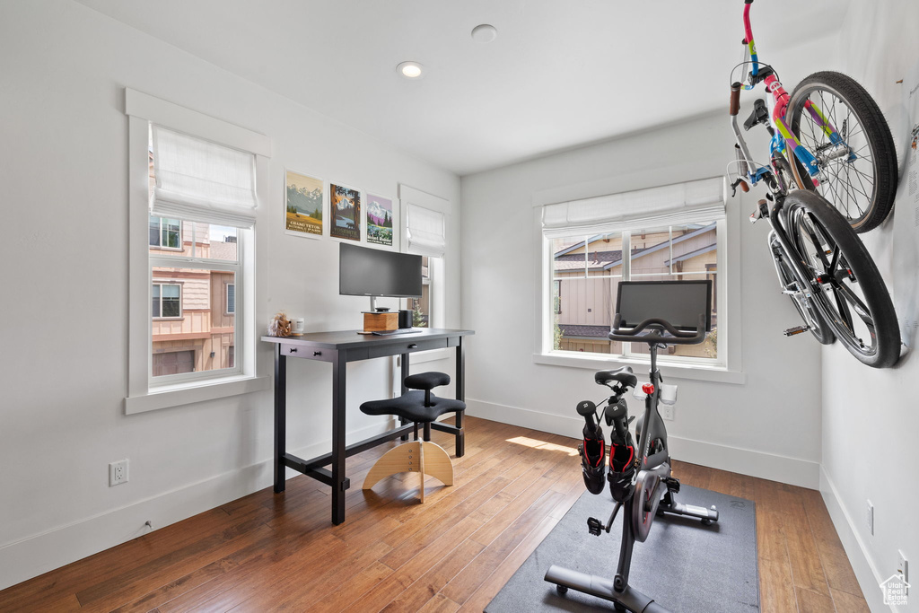 Exercise room featuring healthy amount of natural light, wood finished floors, baseboards, and recessed lighting