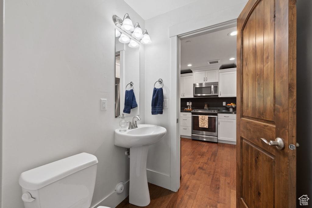 Bathroom featuring toilet, recessed lighting, wood finished floors, a sink, and baseboards