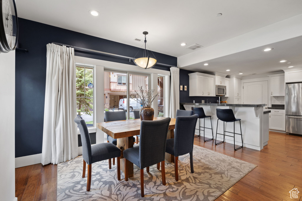 Dining room with light wood finished floors and recessed lighting