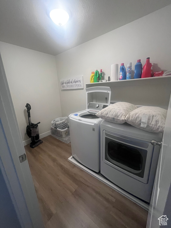 Washroom with washer and clothes dryer, wood finished floors, and baseboards