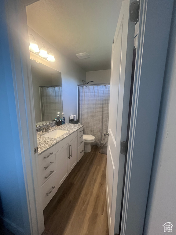 Full bath with vanity, toilet, wood finished floors, and curtained shower