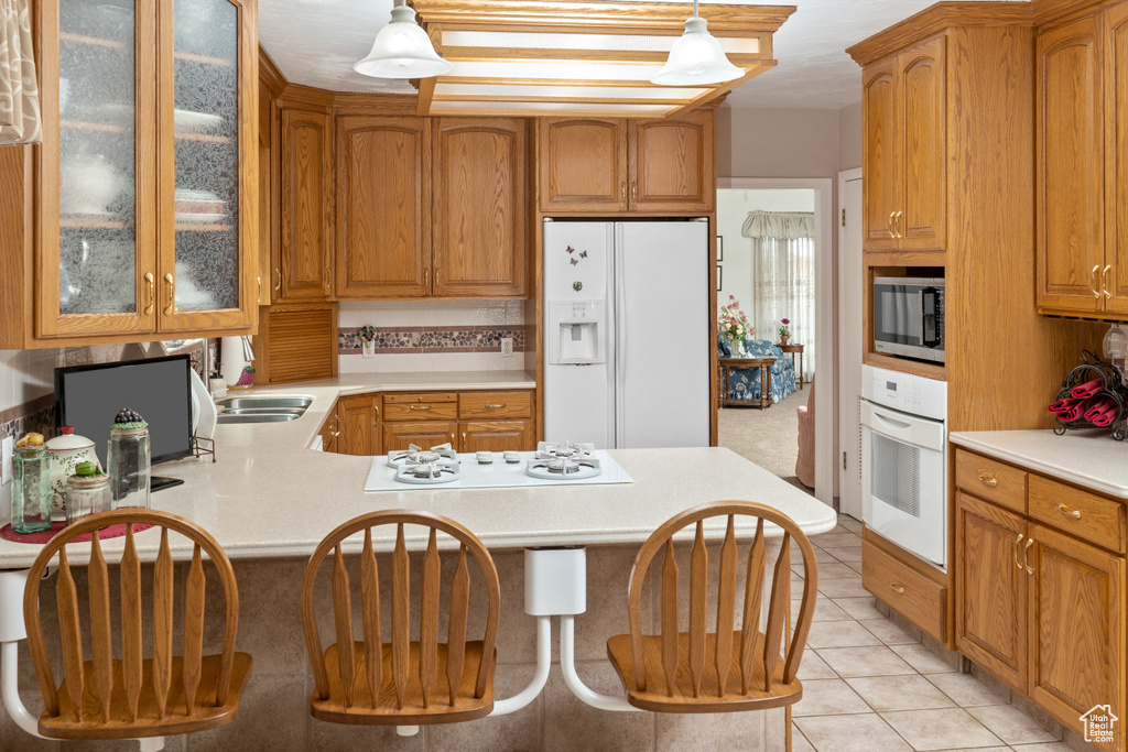 Kitchen featuring white appliances, light countertops, a sink, and glass insert cabinets