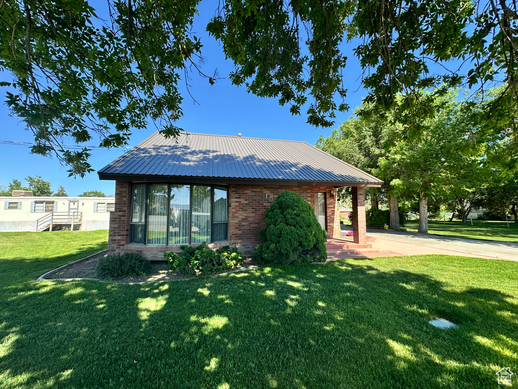 View of front of property featuring brick siding, a front lawn, and metal roof