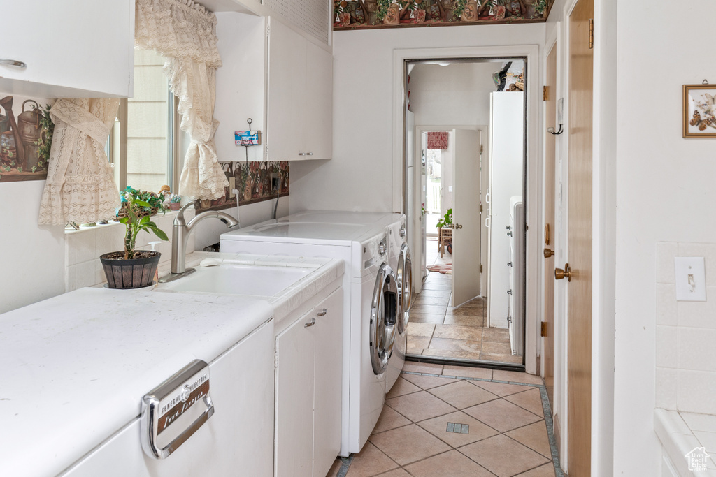 Laundry area with washing machine and dryer, cabinet space, plenty of natural light, and light tile patterned floors