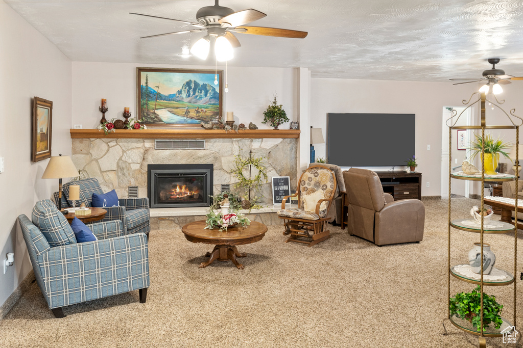 Living room featuring a ceiling fan, carpet flooring, a fireplace, and baseboards