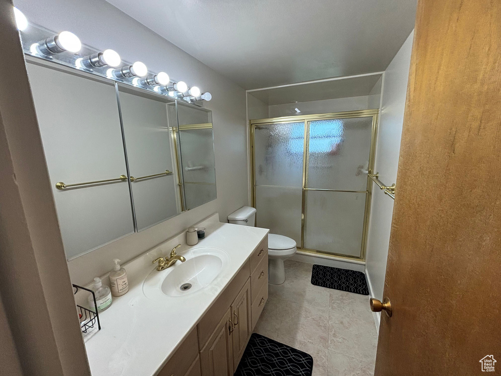 Bathroom with toilet, a stall shower, vanity, and tile patterned floors