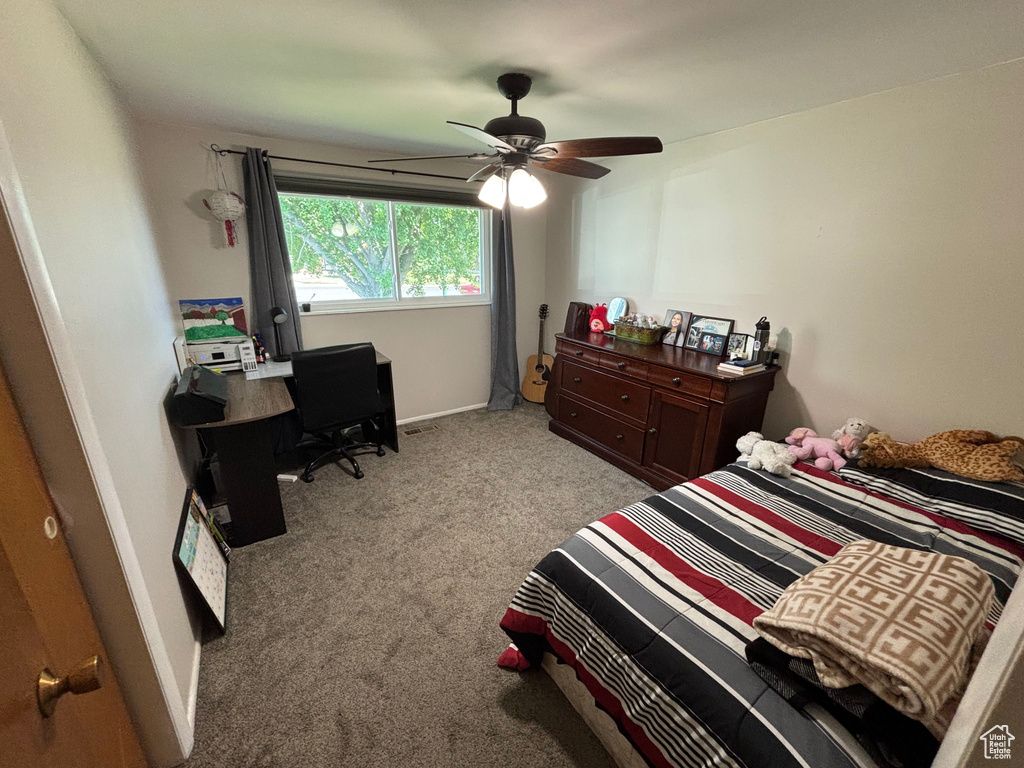 Carpeted bedroom featuring a ceiling fan and a desk