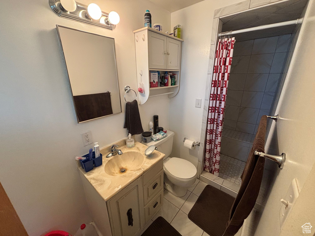 Bathroom with toilet, vanity, a shower stall, and tile patterned flooring
