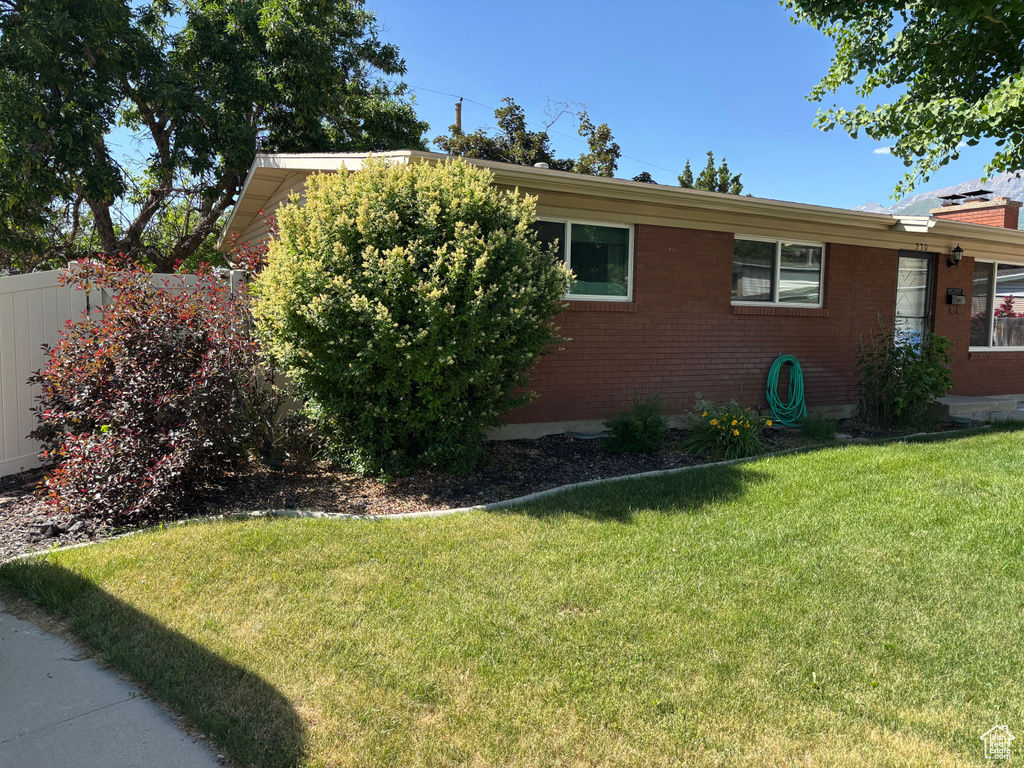 View of home's exterior with brick siding and a lawn