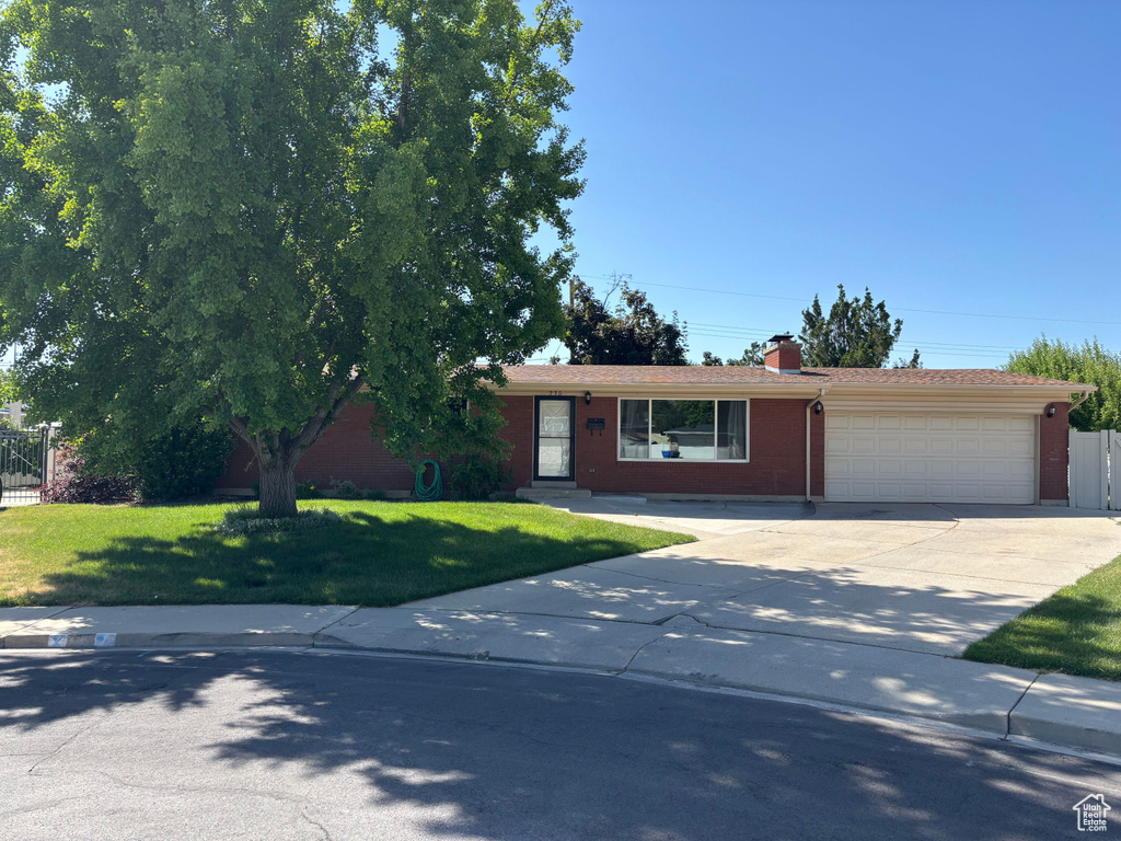 Ranch-style home with an attached garage, driveway, brick siding, and a chimney