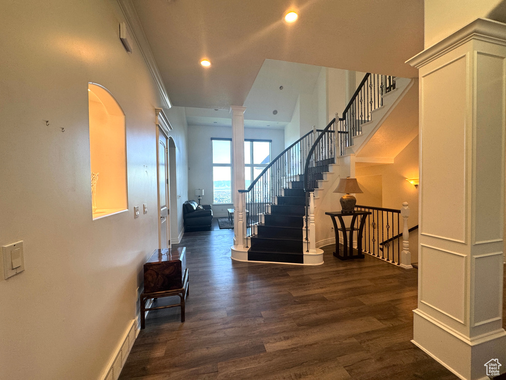 Foyer featuring ornate columns, dark wood-style floors, recessed lighting, stairs, and baseboards