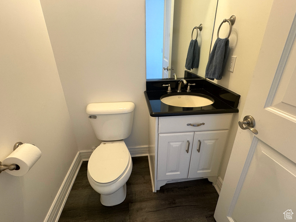 Bathroom featuring toilet, wood finished floors, vanity, and baseboards