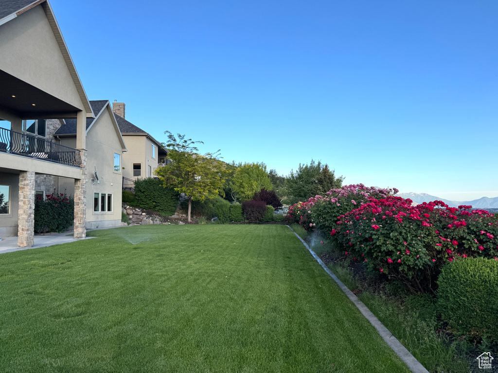 View of grassy yard with a balcony and a mountain view