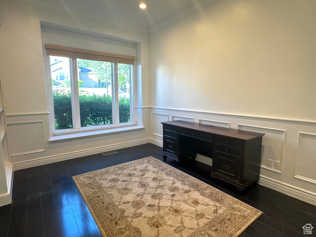 Detailed view of wood finished floors, a decorative wall, wainscoting, and ornamental molding