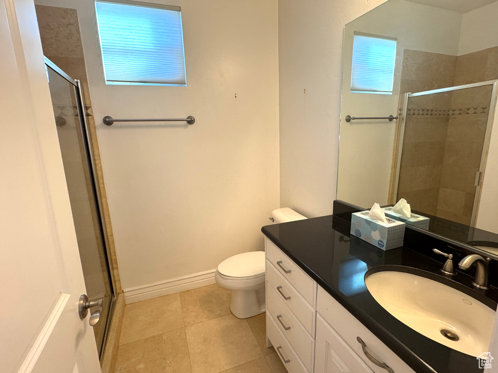 Full bathroom featuring a stall shower, toilet, vanity, tile patterned flooring, and baseboards