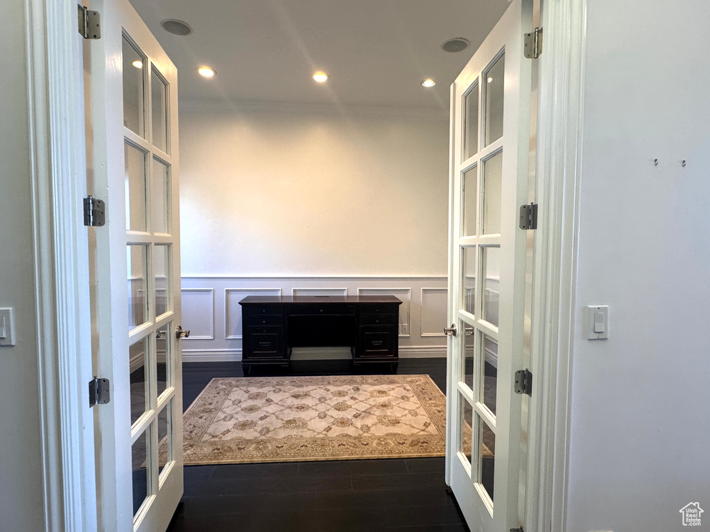Living room featuring french doors, a decorative wall, wainscoting, dark wood-type flooring, and recessed lighting