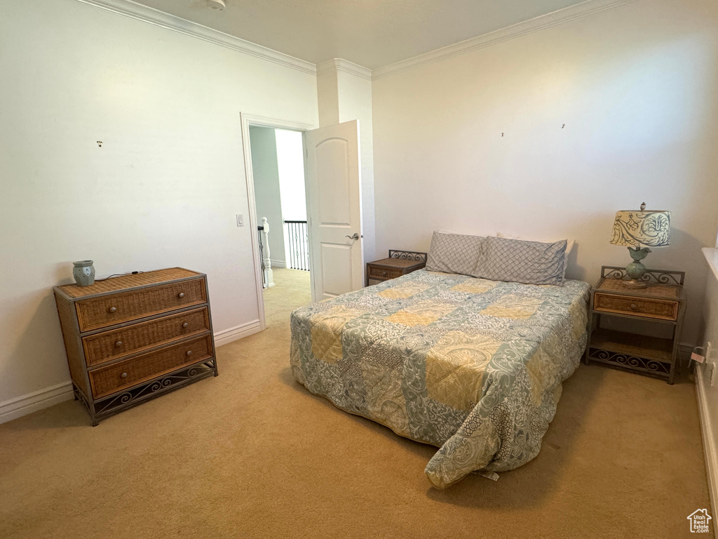 Bedroom featuring ornamental molding, light carpet, and baseboards