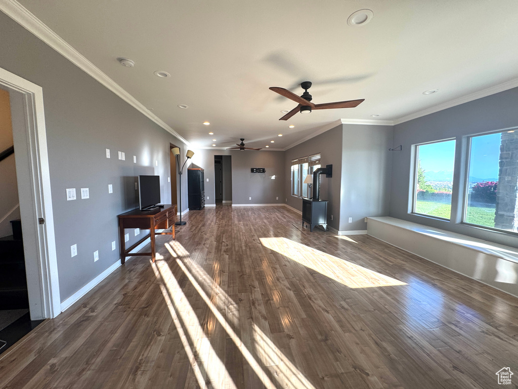 Unfurnished living room with a wood stove, recessed lighting, dark wood finished floors, stairway, and baseboards