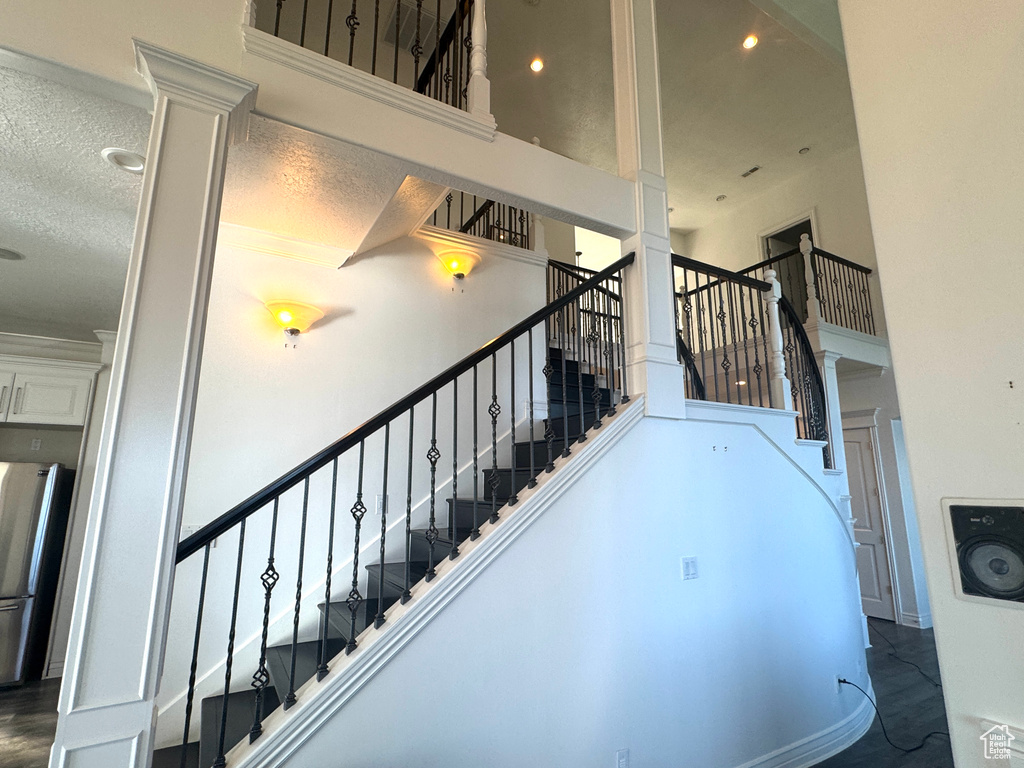 Stairway featuring a high ceiling, decorative columns, and recessed lighting