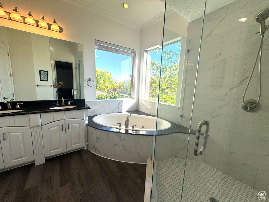 Full bathroom with a bath, a marble finish shower, wood finished floors, crown molding, and double vanity