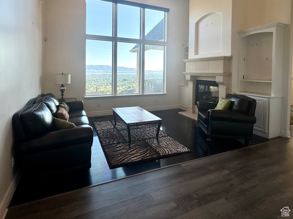Living area with dark wood finished floors, a glass covered fireplace, baseboards, and a mountain view