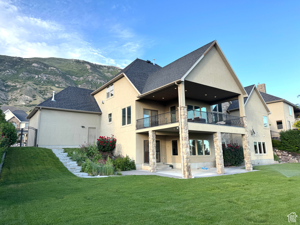 Back of house with a balcony, a yard, a patio area, and stucco siding