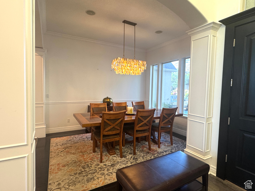 Dining area with arched walkways, dark wood-style floors, crown molding, a chandelier, and baseboards